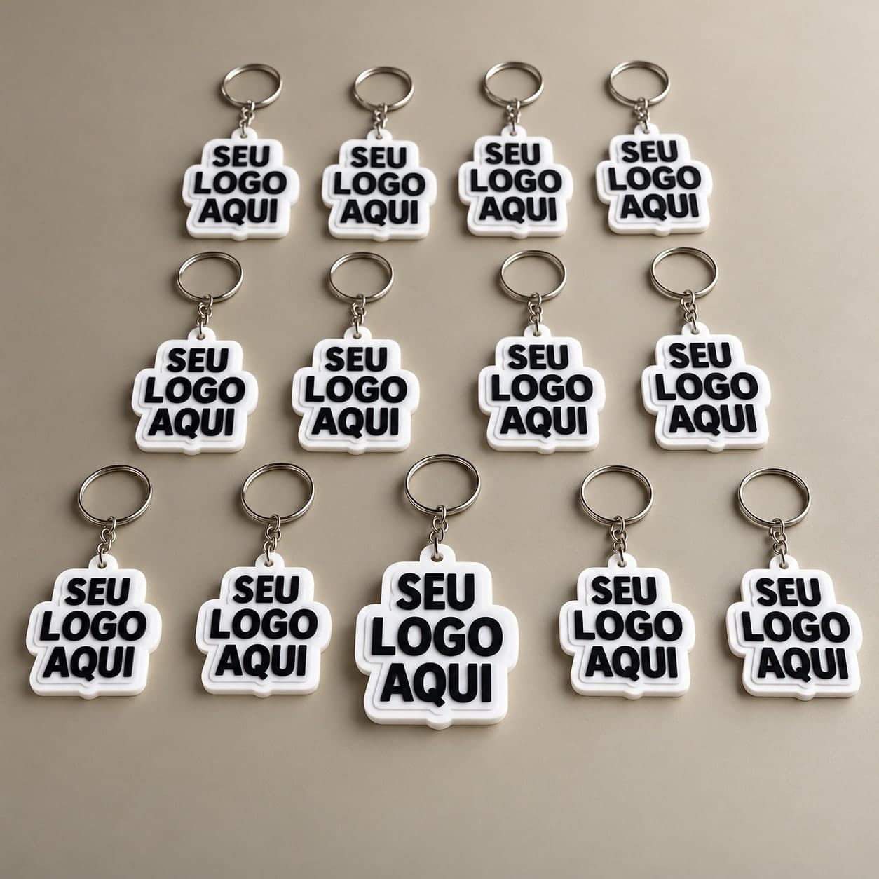 Mão segurando um chaveiro branco impresso em 3D com “Seu logo aqui” em relevo, com um lote de chaveiros iguais sobre a mesa
