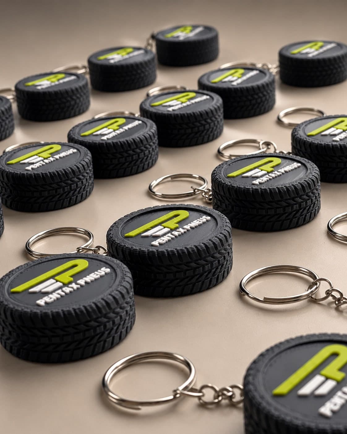 Chaveiros em formato de pneu preto, com logo verde-limão e branco no centro, enfileirados sobre uma mesa clara