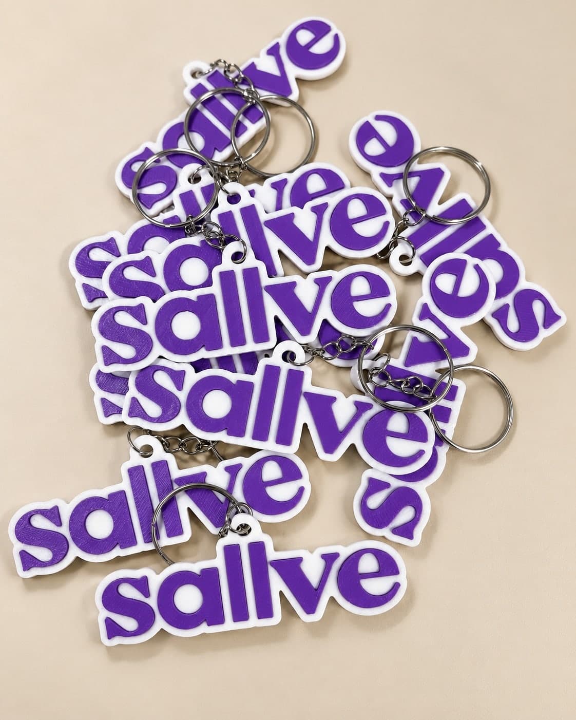 Pilha de chaveiros brancos com logo de letras roxas em relevo e argolas de metal